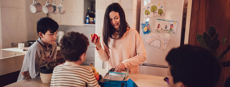 Woman and children in a kitchen preparing food together.