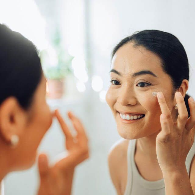 Woman doing skincare in front of a mirror