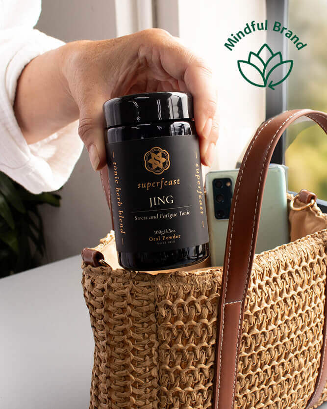 Hand holding a black container labeled 'superfeast' next to a woven bag with a 'Mindful Brand' logo.