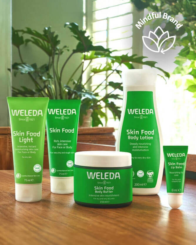 Weleda skincare products on a wooden surface with a plant in the background.