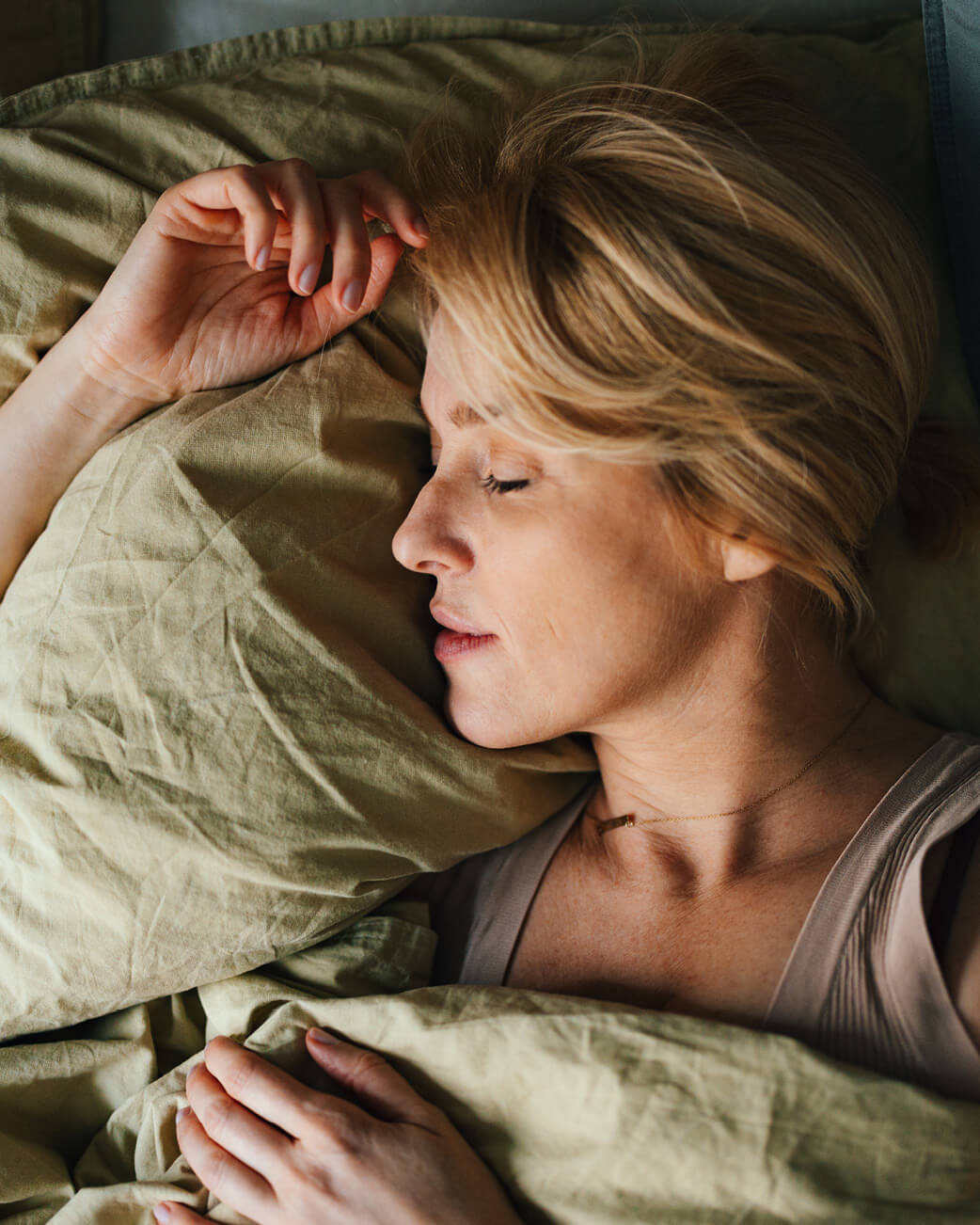 Woman sleeping peacefully with green bedding