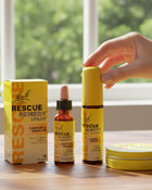 Bach Rescue Remedy products including spray, dropper, and box on a wooden surface with a window in the background.