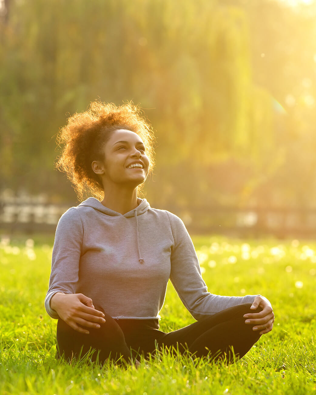 Woman meditating on grass with a blurred natural background