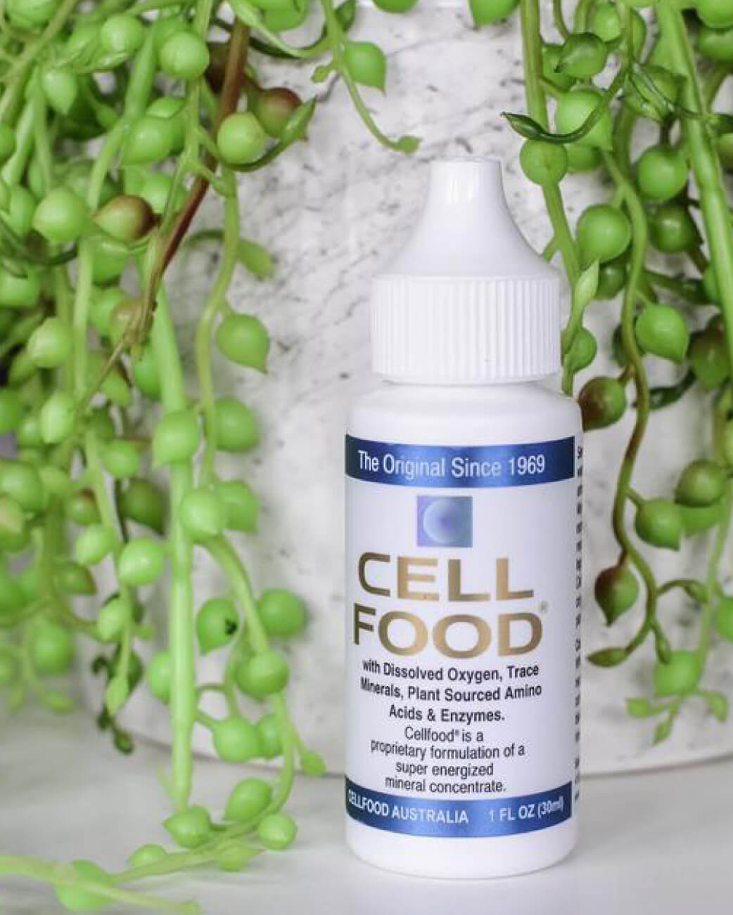 Bottle of Cell Food supplement with green plants in the background
