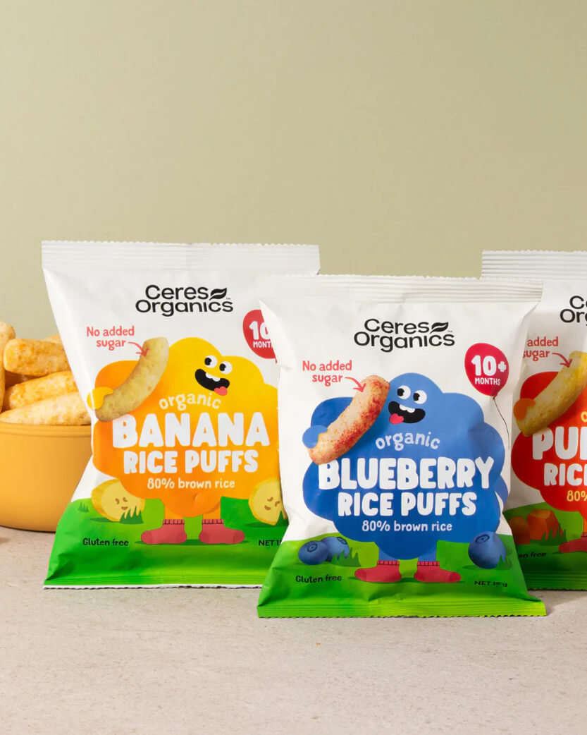 Ceres Organics banana and blueberry rice puffs packaging on a beige background.