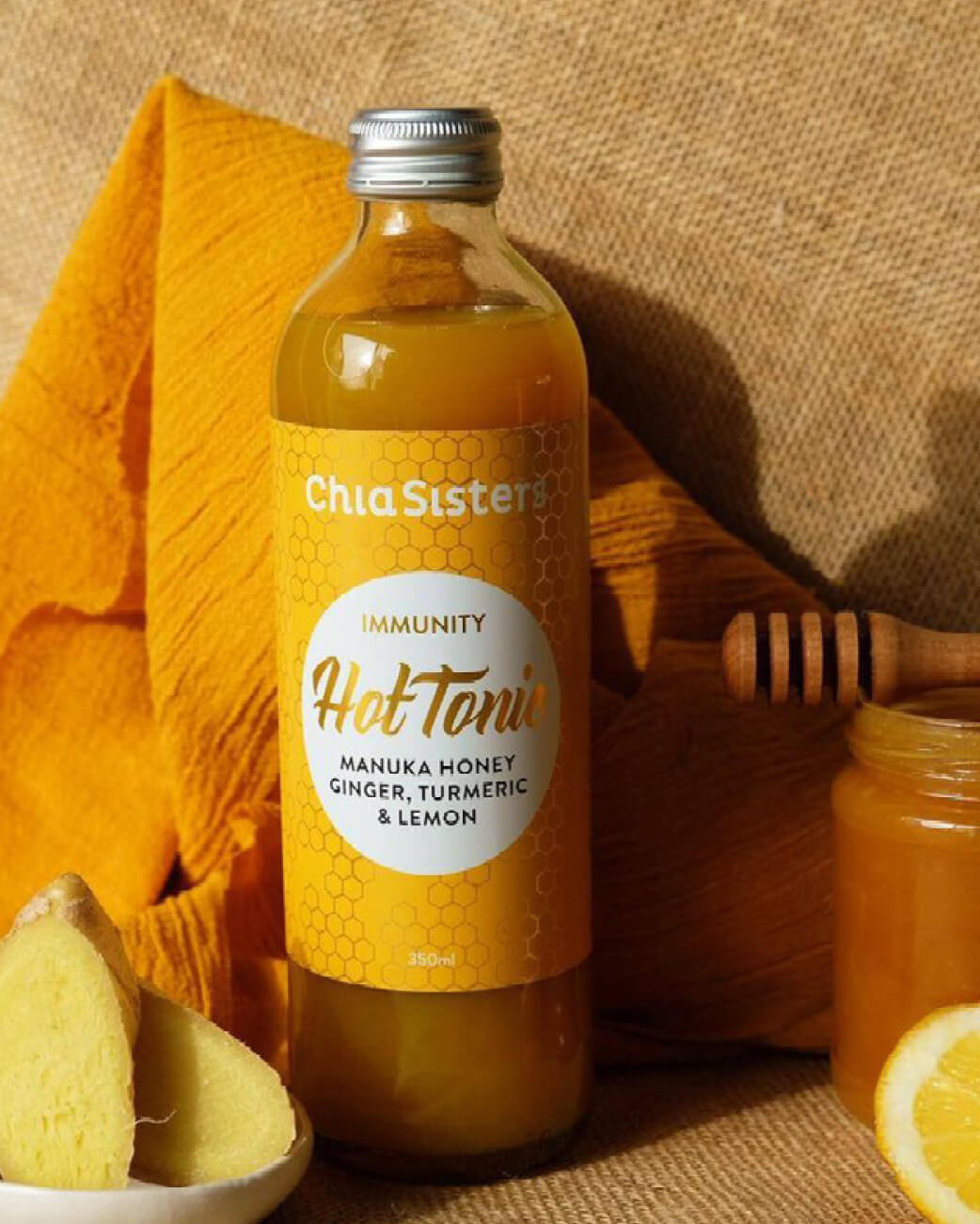 Bottle of Chia Sisters Hot Tonic with ingredients on a textured background