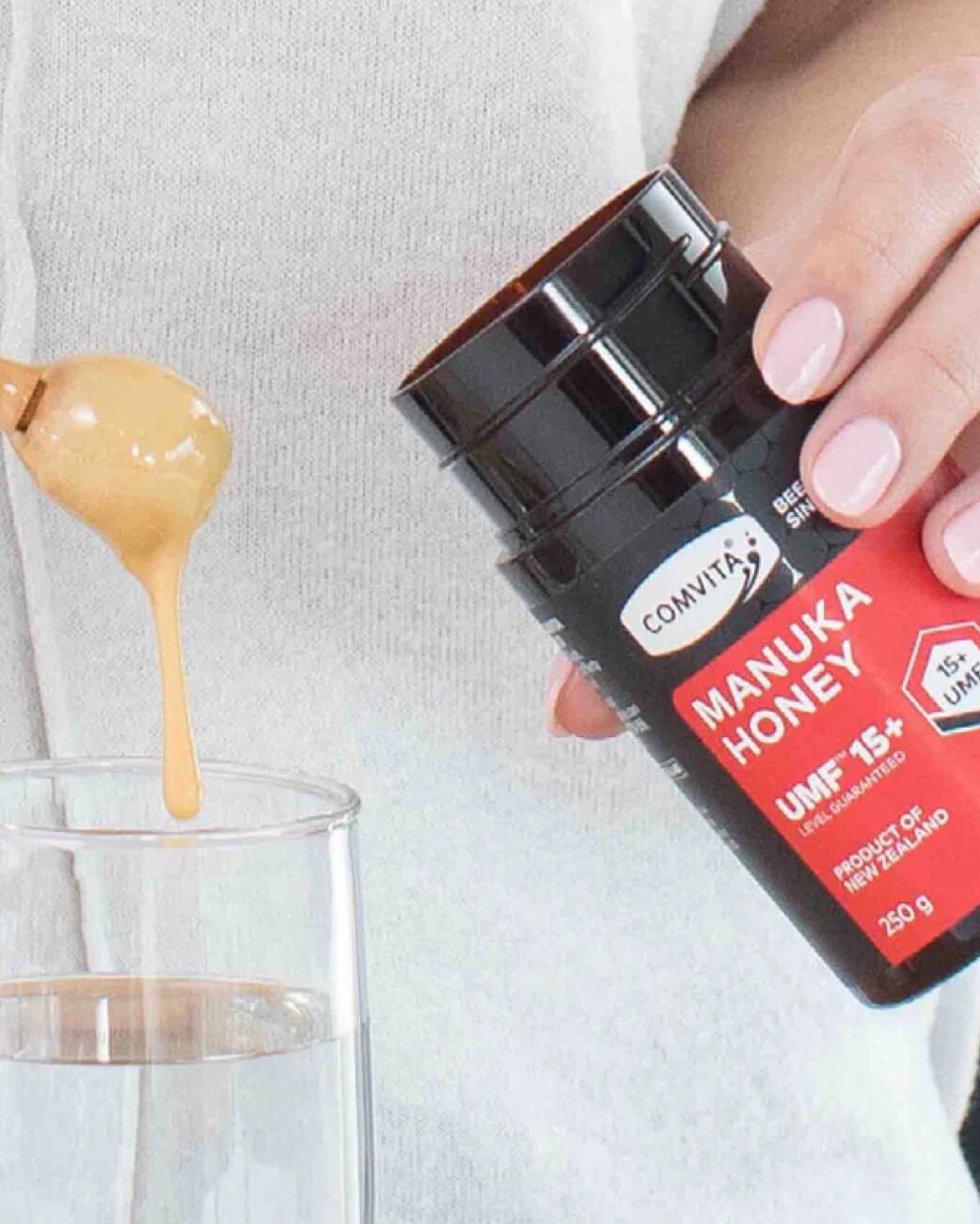 Manuka honey being drizzled into a glass with a Convita Manuka Honey container.
