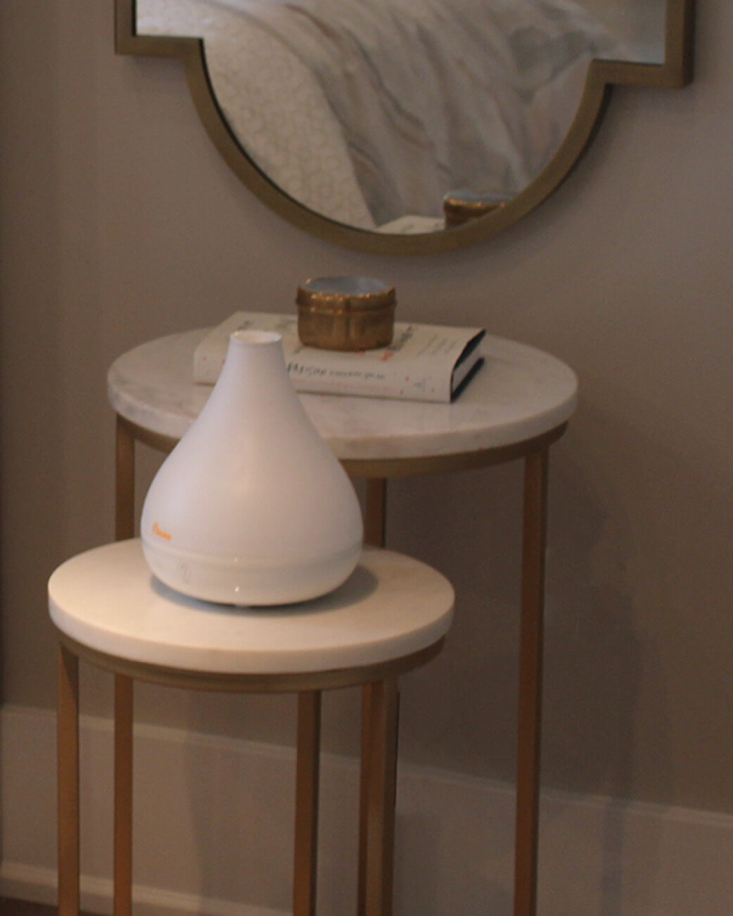 White diffuser on a marble side table with a mirror in the background