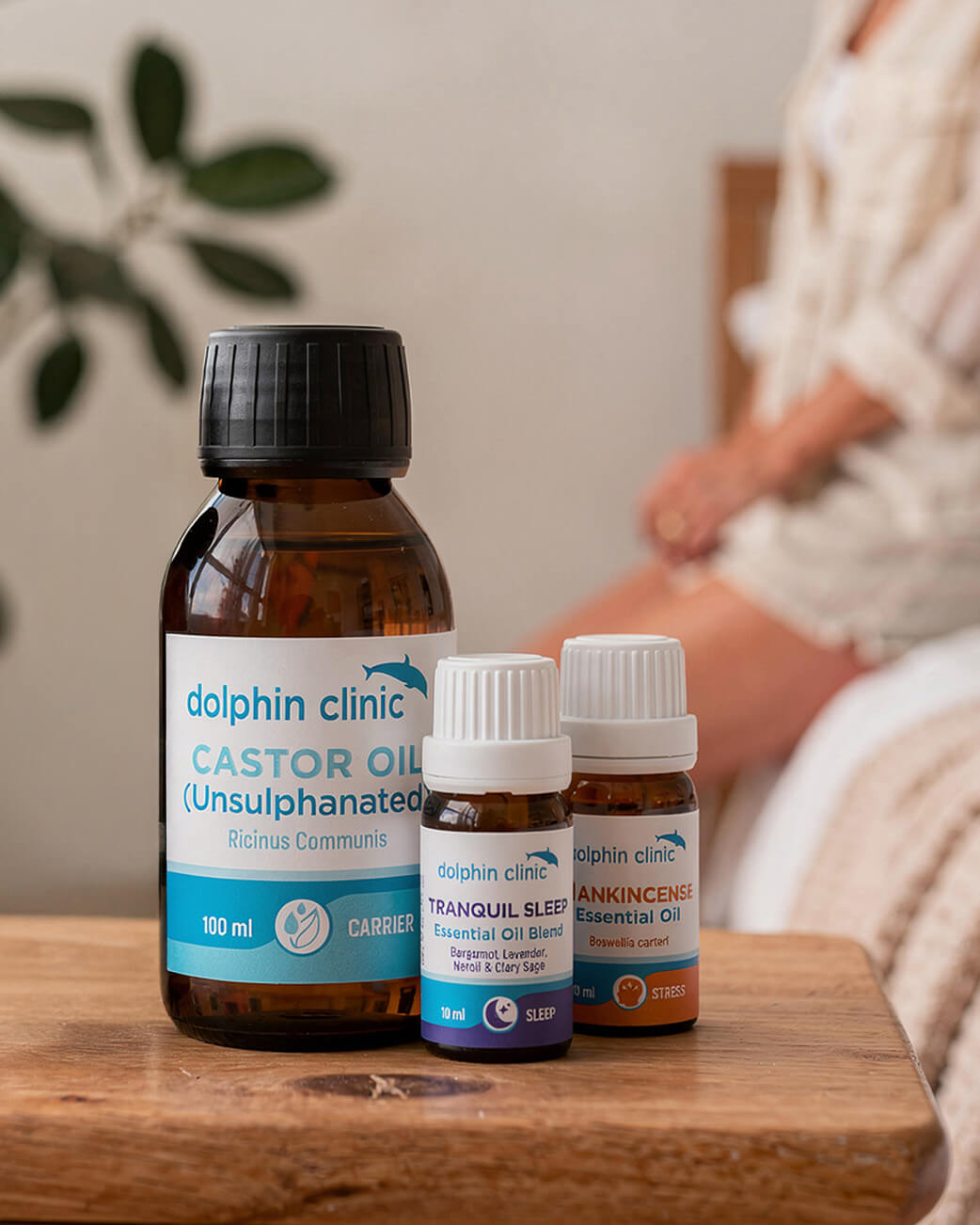 Bottles of Dolphin Clinic essential oils on a wooden surface with a blurred background.
