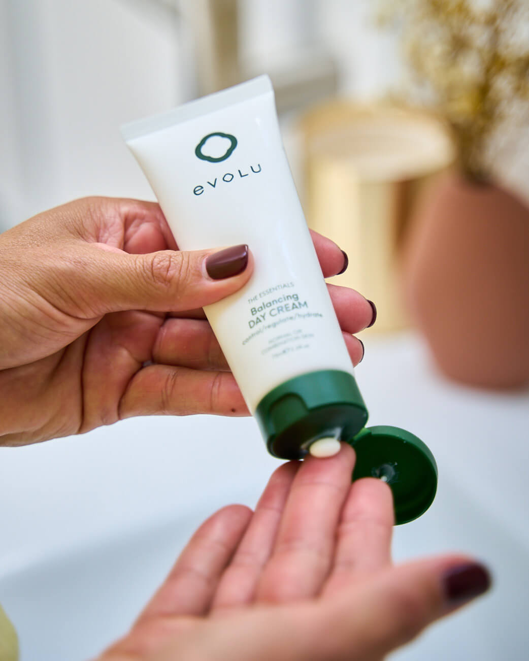 Person applying Evolu cream to their hand with a blurred background.