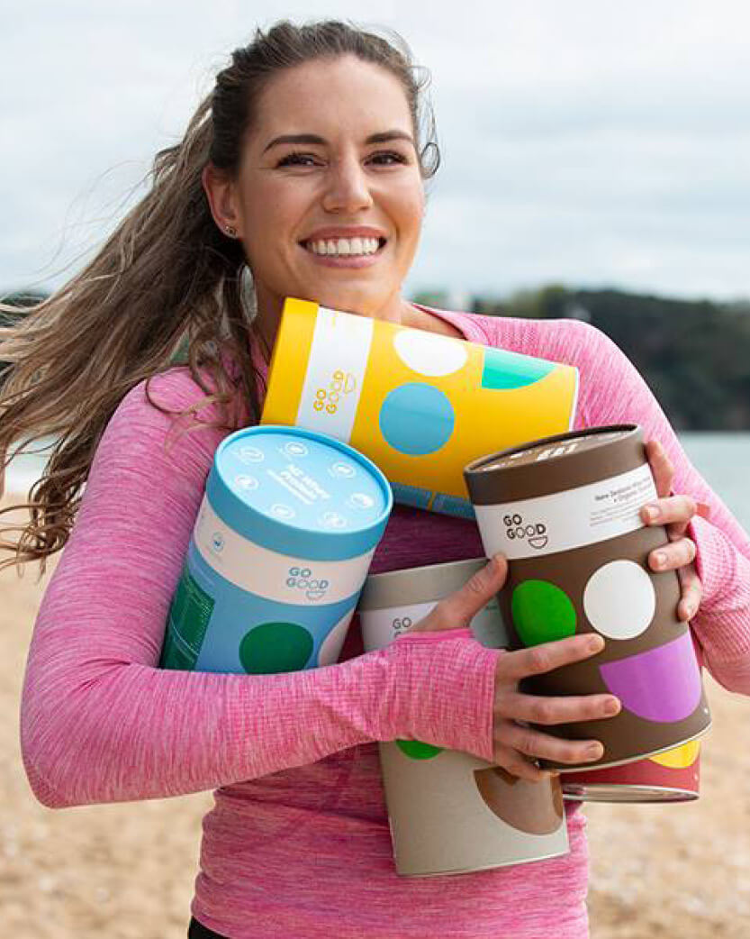Woman holding colourful tubs with a beach background.