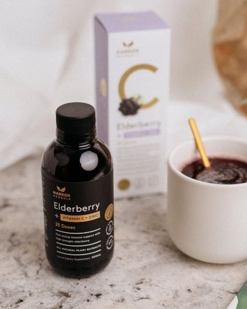 Bottle of Elderberry supplement with a box and cup in the background on a marble surface.