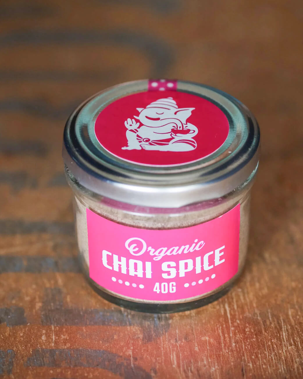 Jar of organic chai spice on a wooden surface.