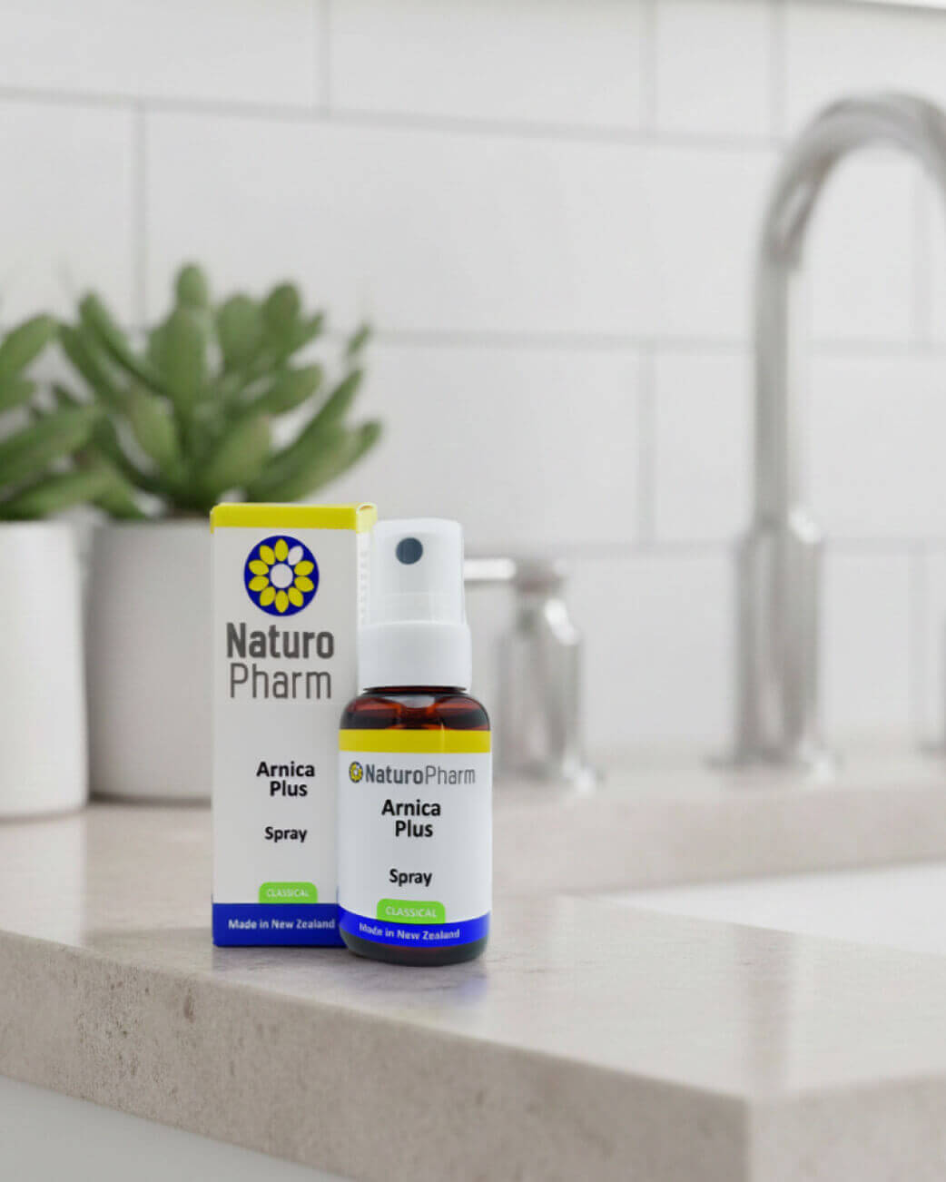 Naturopathic Arnica Plus Spray bottle and packaging on a kitchen counter.