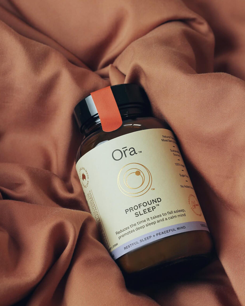 Bottle of Ora Profound Sleep supplement on a brown fabric background.