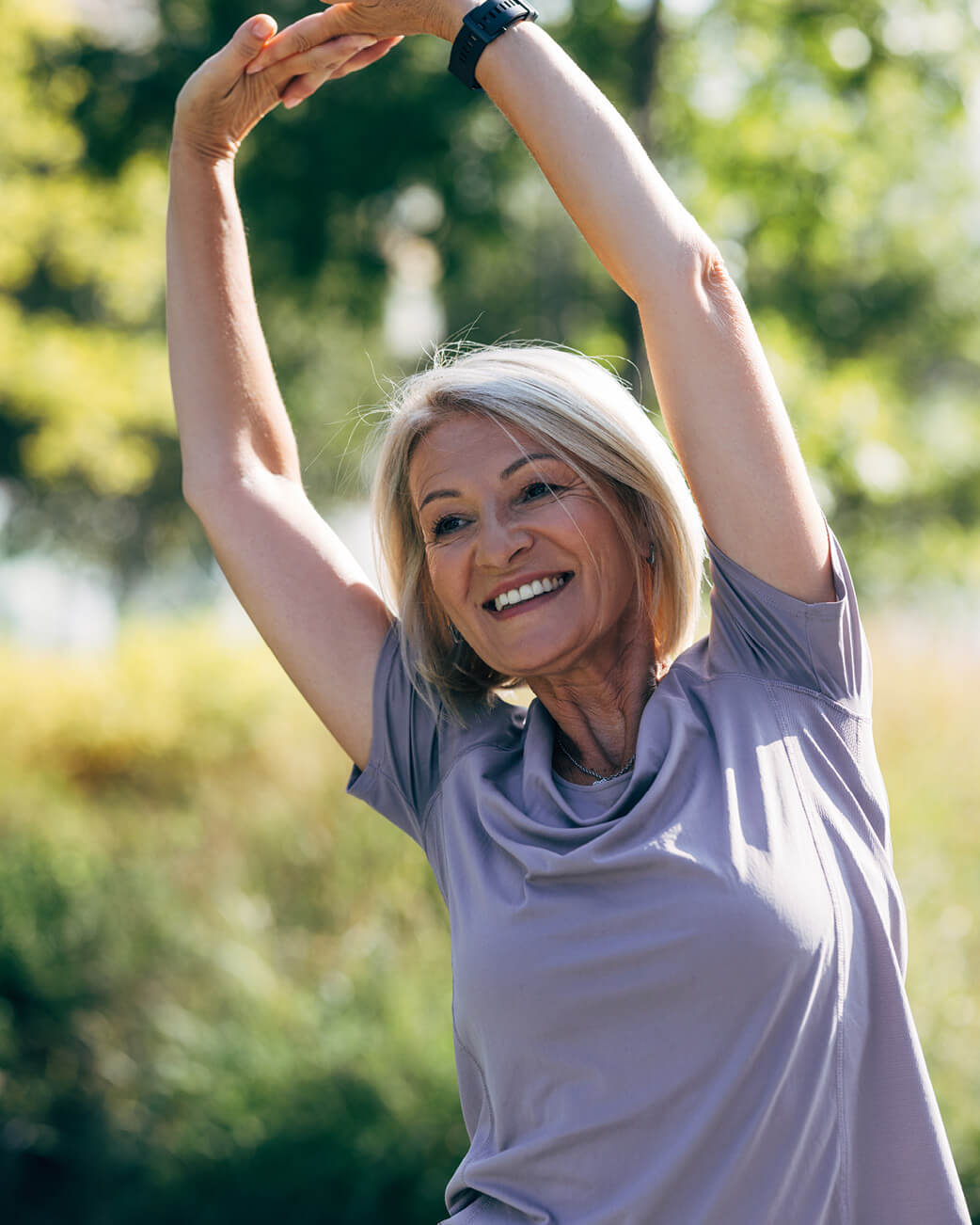 Woman stretching outdoors with a blurred natural background.