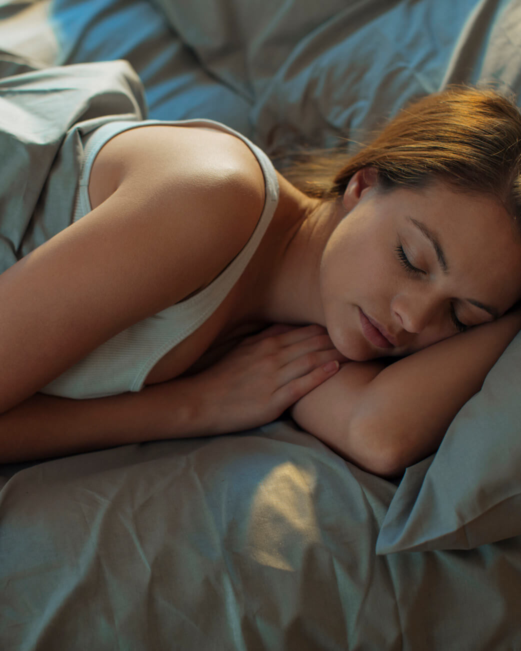 Woman sleeping peacefully in bed with soft lighting.