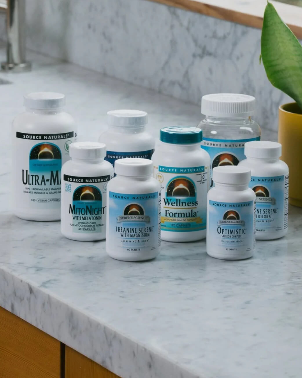 Collection of Source Naturals supplement bottles on a marble countertop.