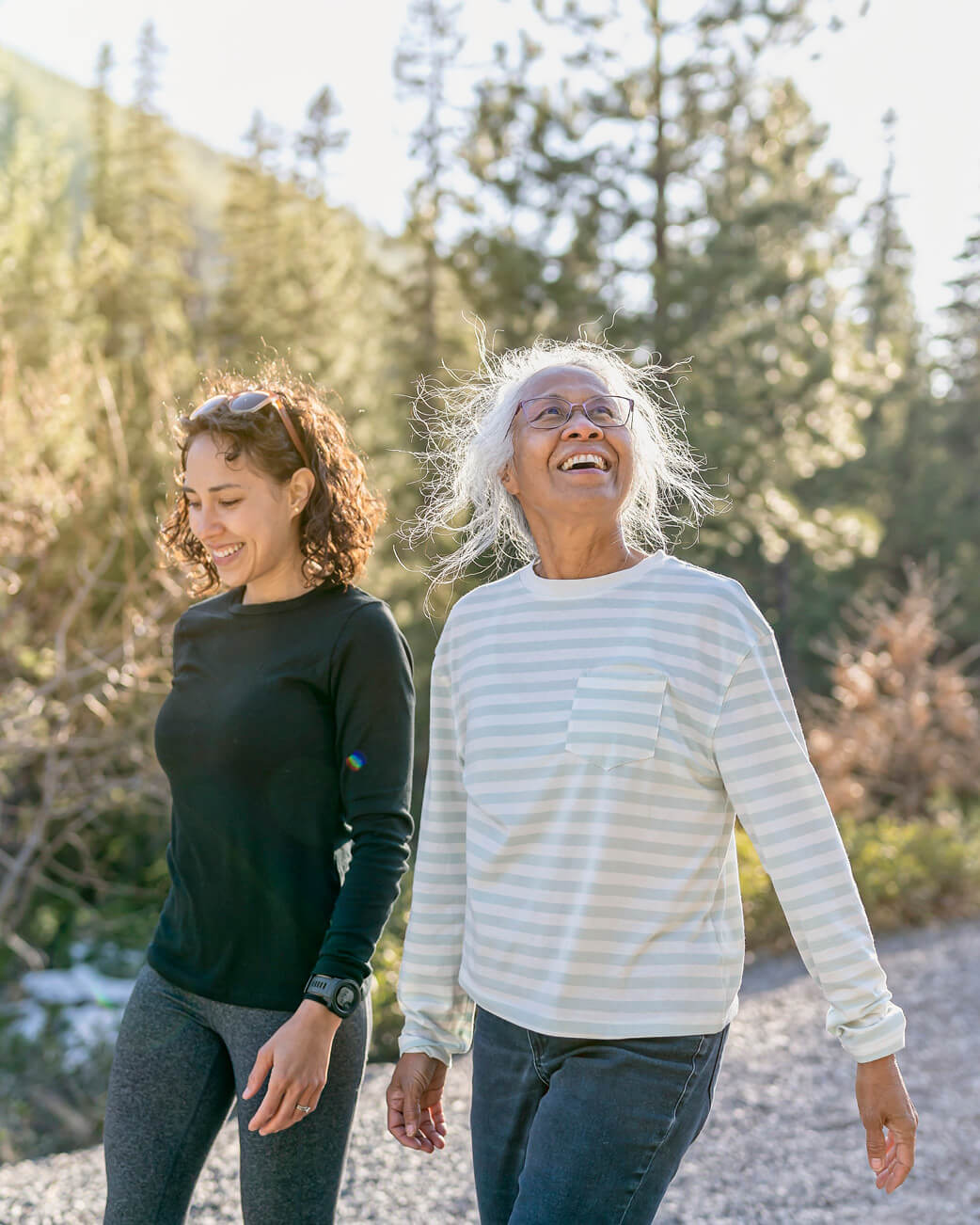 Two people walking together in a forested area.