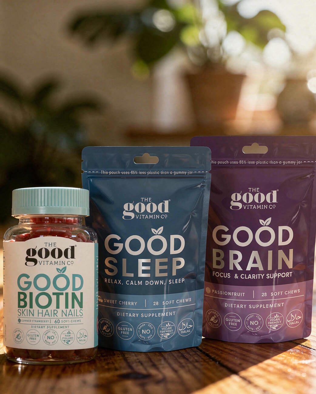 Supplement packages from The Good Vitamin Co on a wooden surface with a blurred natural background.