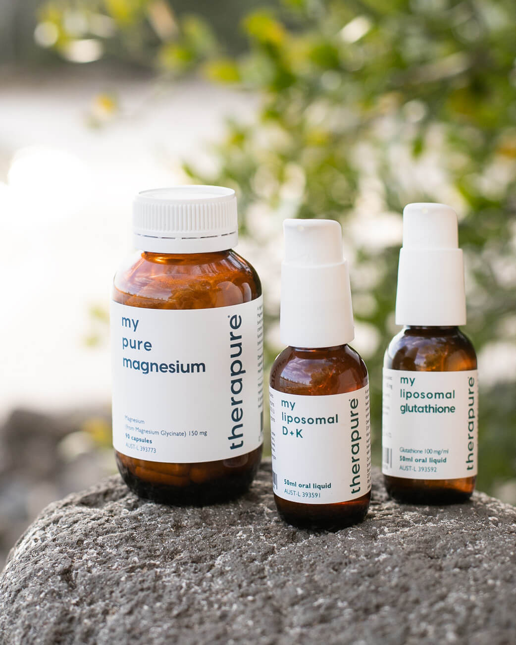 Three bottles of Therapure supplements on a rock with a natural background.