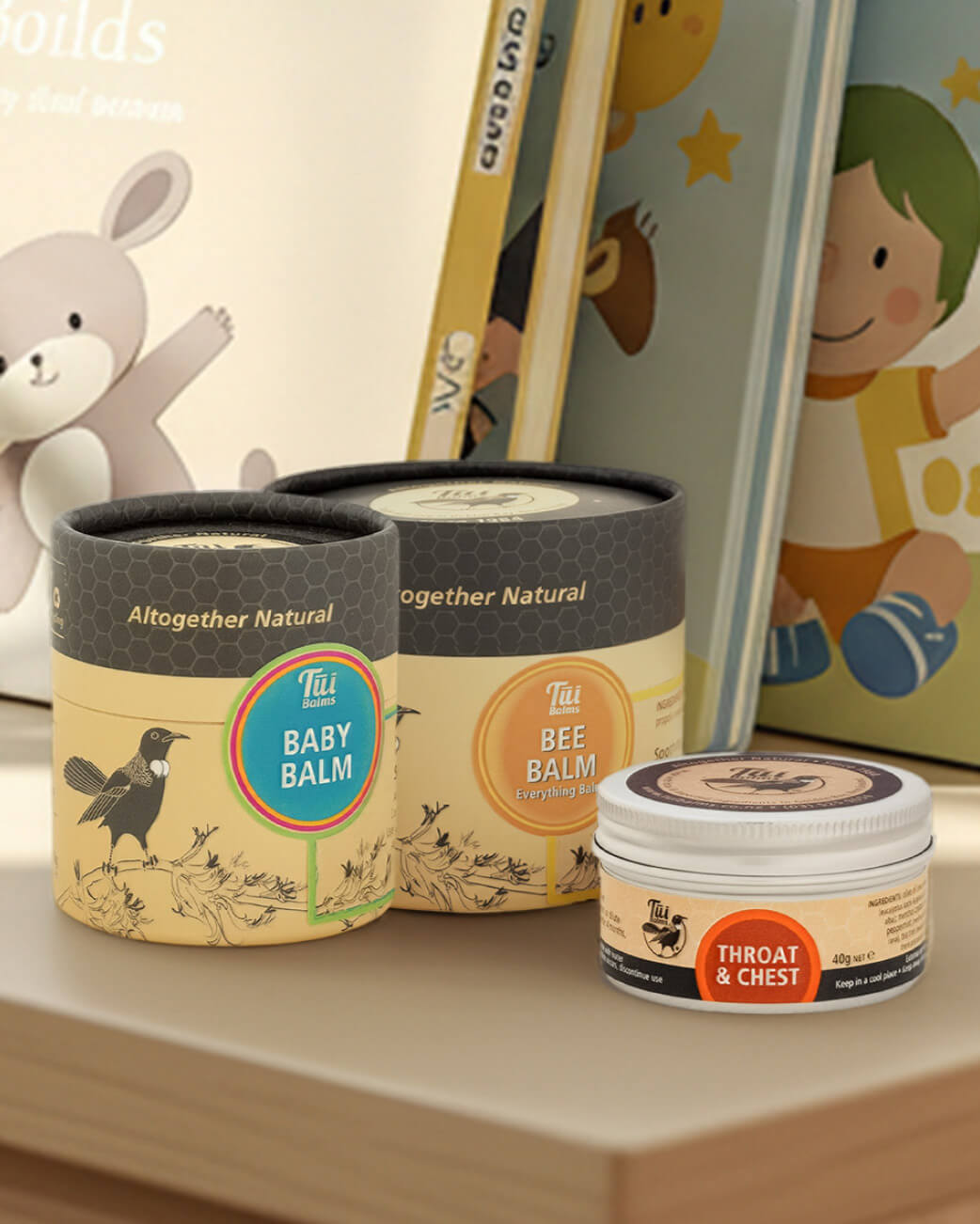 Three containers of 'Altogether Natural' balm on a shelf with children's books and toys in the background.