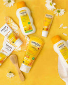 Weleda baby products on a yellow background with flowers.