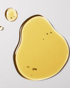Yellow oil droplet and pool on a light grey background.
