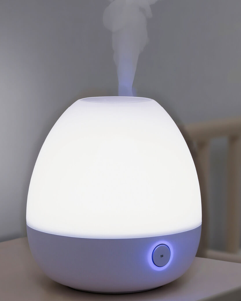 White humidifier emitting mist on a blurred background.