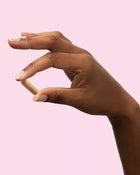 Hand with painted nails against a pink background.