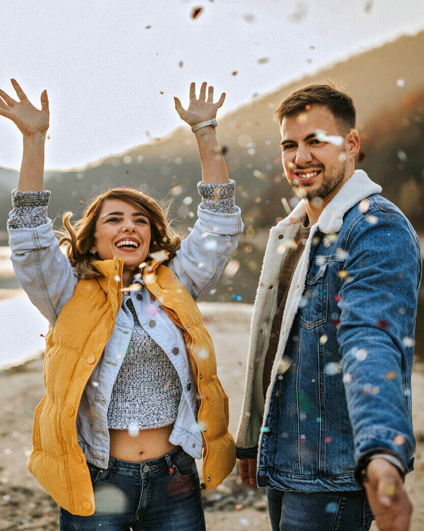 Two people enjoying a moment outdoors with confetti falling around them.