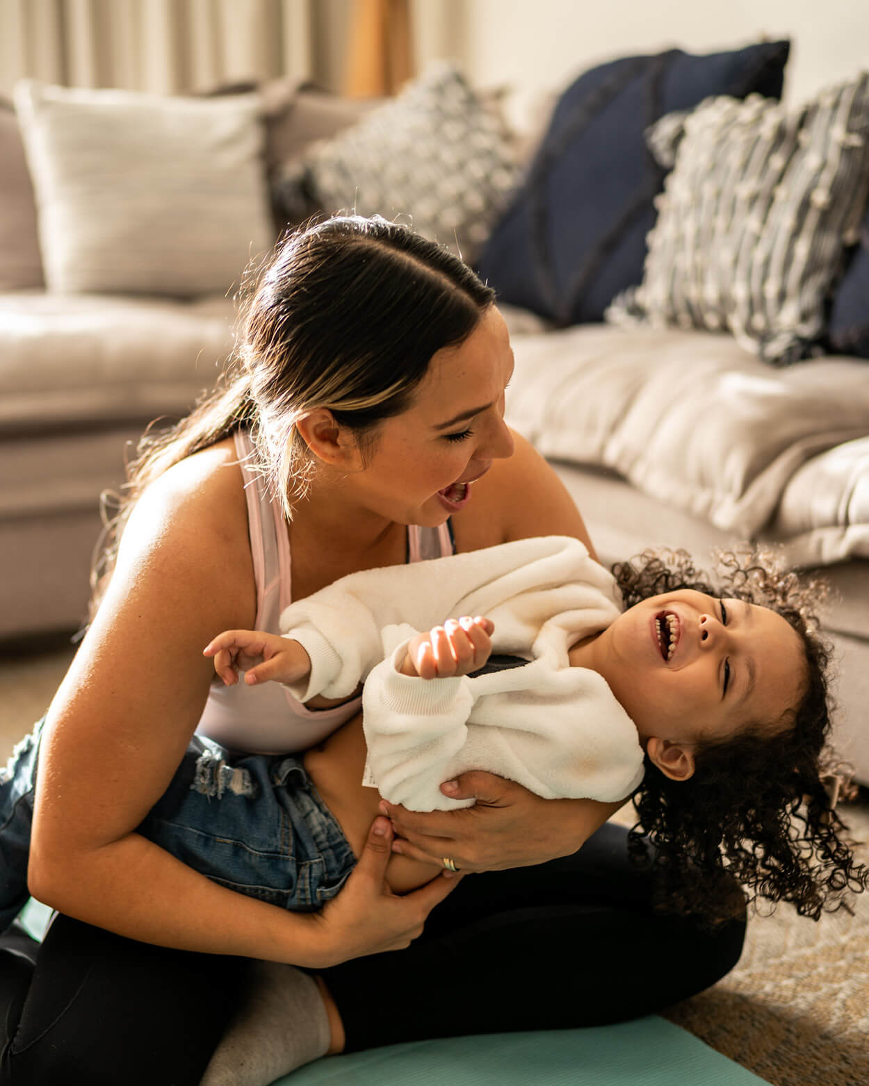 Woman holding a baby in a living room setting.