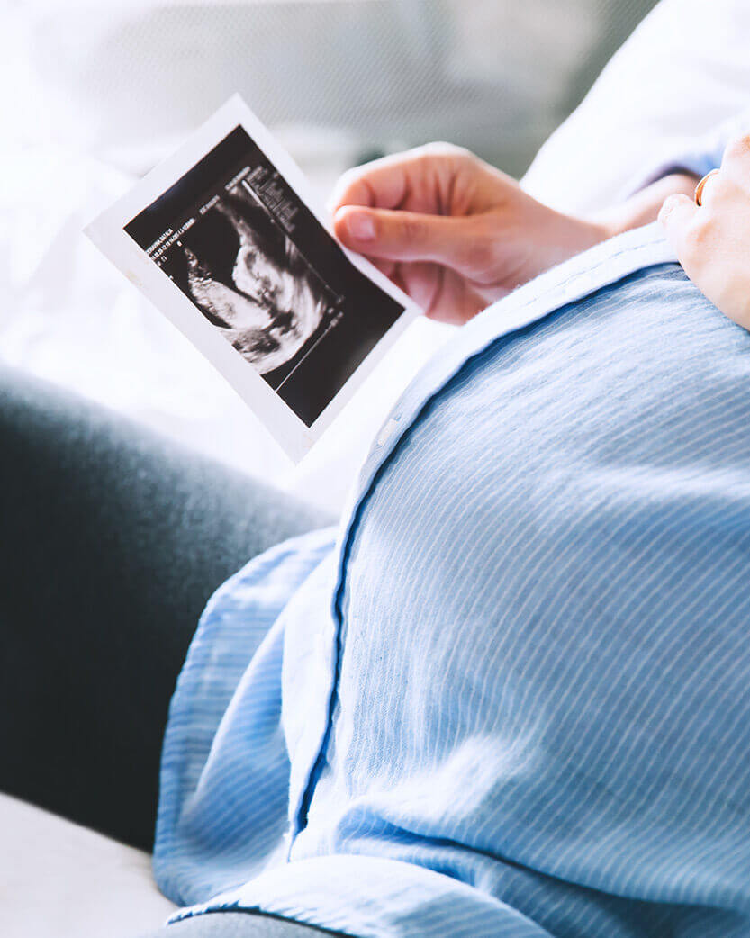 Person holding an ultrasound image of a baby.