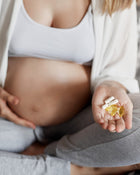 Pregnant woman holding supplements in her hand.