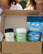 Box containing health and wellness products including 'Lion's Mane', 'Matcha Powder', and 'The Salt of the Earth' product.