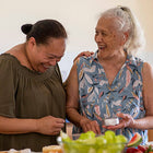 Two women laughing with food in front of them.