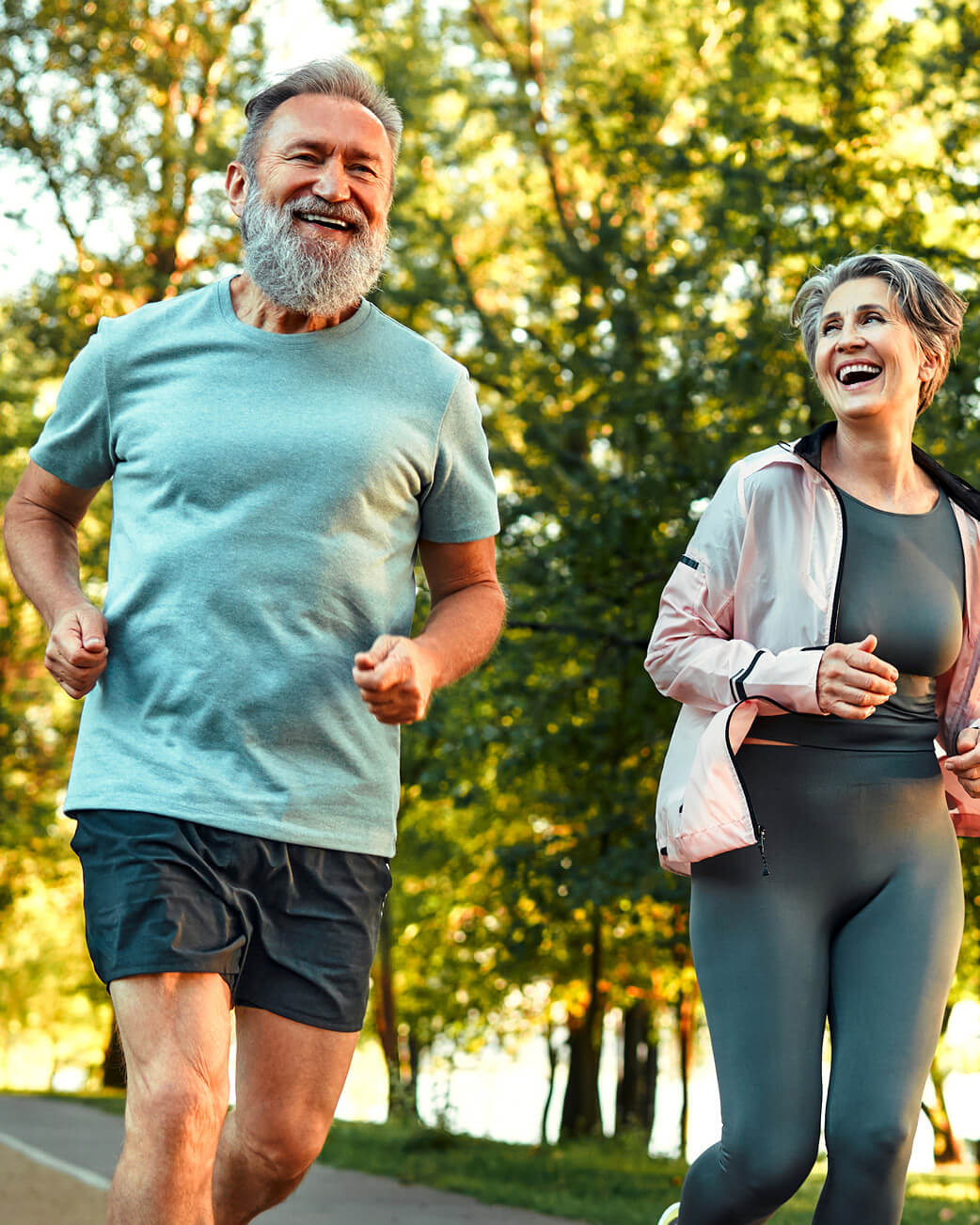 Two people jogging outdoors on a path with trees in the background.