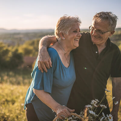 Senior couple embracing in a field with a scenic background.