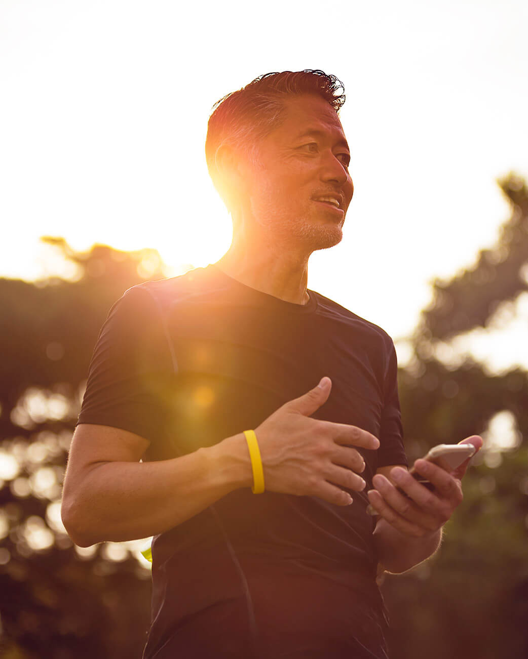 Man using a smartphone outdoors with a warm, blurred background.