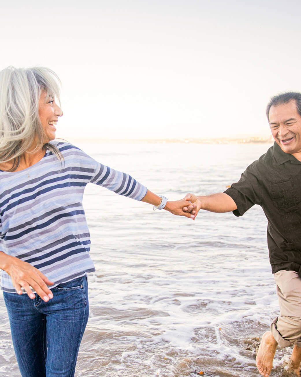 Two people holding hands on a beach.