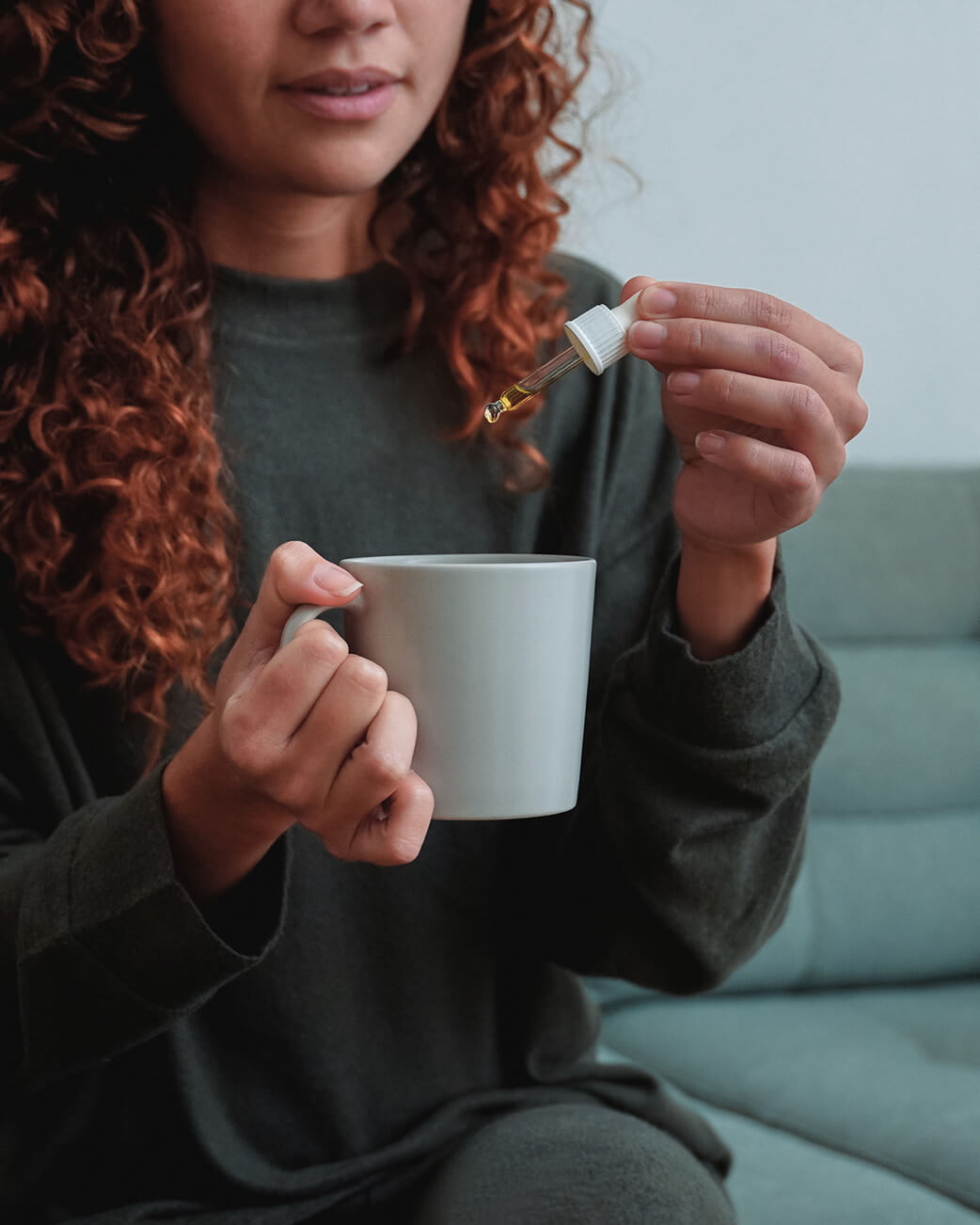 Woman using a dropper over her mug.
