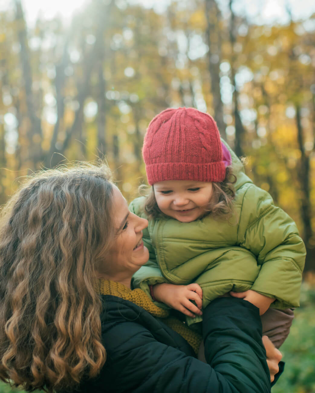 Mum holding a child in a forest.