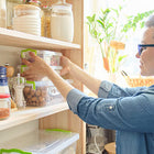 Woman stacking clear plastic containers on a pantry shelf.