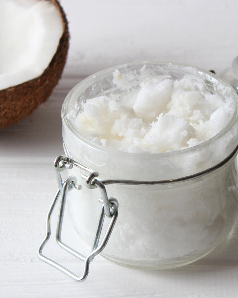 coconut oil and flakes in a glass jar on a white background