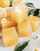 Yellow jelly cubes with lemon slices and leaves on a speckled surface