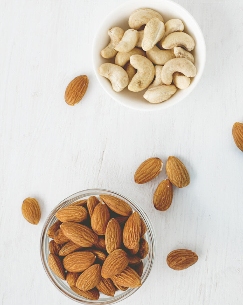 Bowl of almonds and cashews on a white surface
