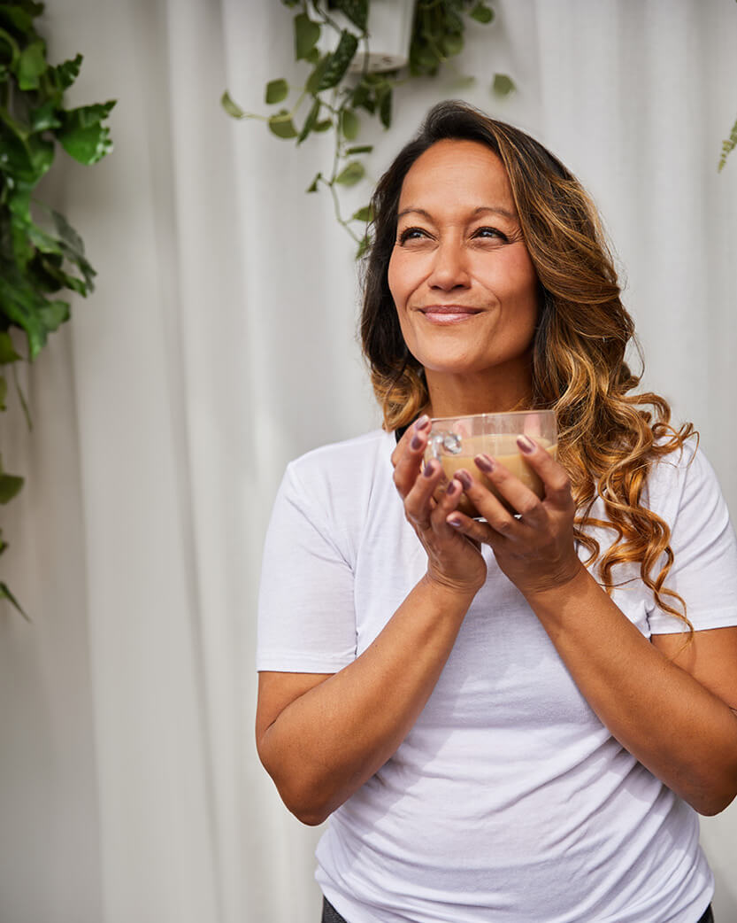 Woman holding a cup with greenery in the background