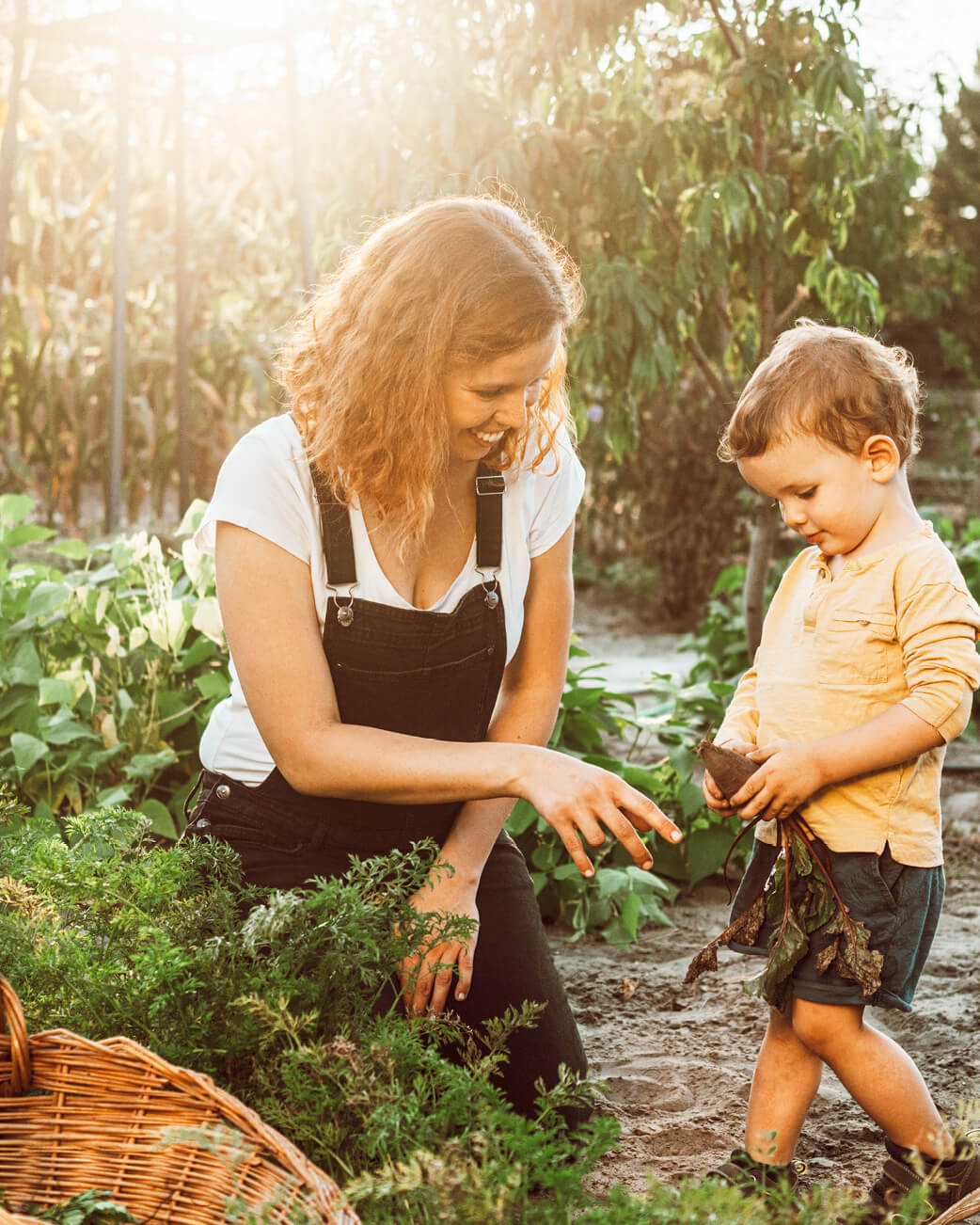 Woman and child in a garden, surrounded by plants and greenery.