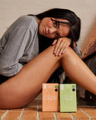 Person sitting on a floor with TOTM period products in the foreground.