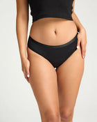 Person wearing black high-waisted underwear on a plain background.
